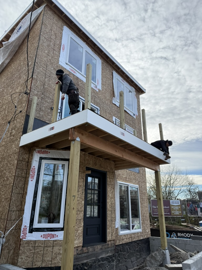Crew members wrapping the balcony deck posts and installing PVC trim