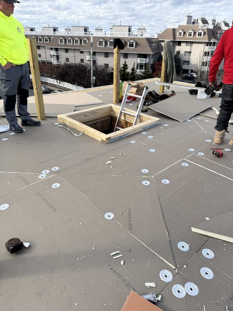 Crew installing insulation board on the flat roof with mechanical fasteners